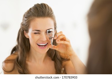 Young woman using eyelash curler in bathroom - Shutterstock ID 170783903