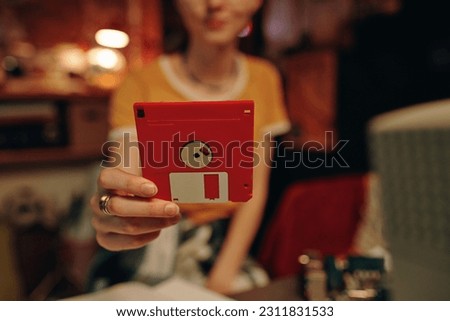 Young woman using floppy disk to save information from computer