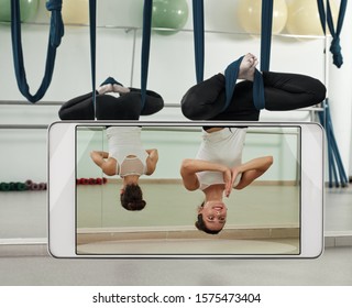 Young woman using hammock and practicing fly yoga, concept of new features of smart device. Original items have been removed from the front panel - Powered by Shutterstock