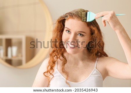 Young woman using henna hair dye at home