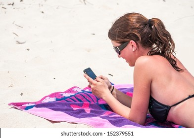 A Young Woman Using Her Cell Phone At The Beach