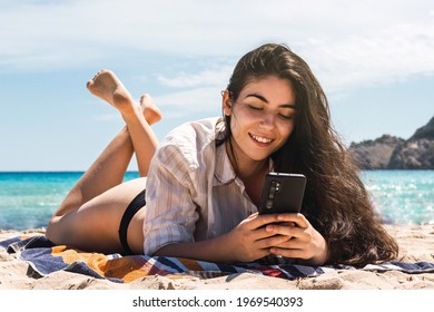 young woman using her mobile in the beach