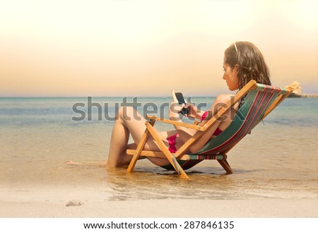 Young woman using her smart phone at the beach