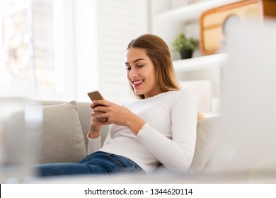 Young woman using her smartphone at home - Shutterstock ID 1344620114