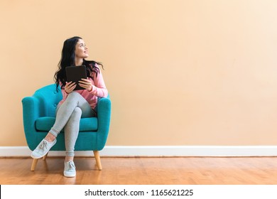 Young Woman Using Her Tablet On A Blue Chair