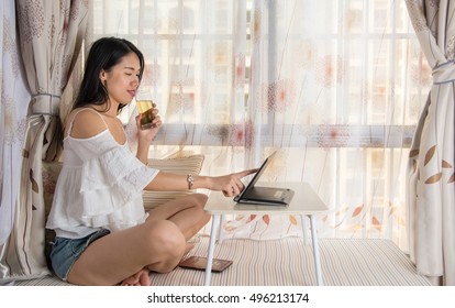 Young Woman Using Lap Top By The Window At Home