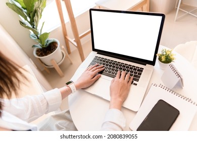 Young Woman Using Laptop With Blank Screen, Online Learning On Pc, Elearning, Watching Movie. Over Shoulder Closeup View