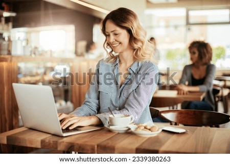 Young woman using a laptop in a cafe while having a cup of coffee Foto stock © 
