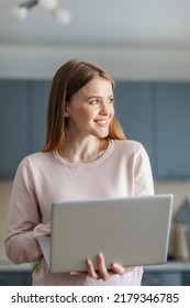 Young woman using laptop computer, looking away, thinking and smiling cheerfully at home. Female working online, studying remotely or browsing Internet on pc - Shutterstock ID 2179346785