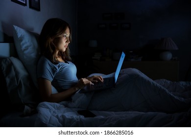 Young Woman Using A Laptop In Her Bed At Night