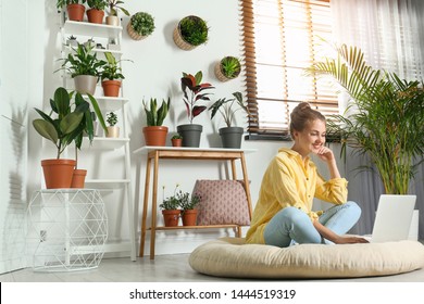 Young Woman Using Laptop In Room With Different Home Plants