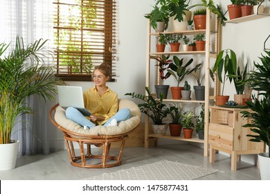 Young Woman Using Laptop In Room With Different Home Plants