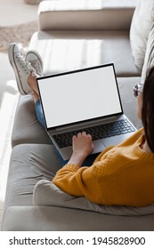 Young woman using laptop screen blank, mockup lying on the sofa at home