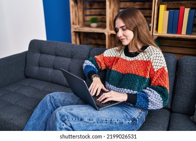 Young Woman Using Laptop Sitting On Sofa At Home