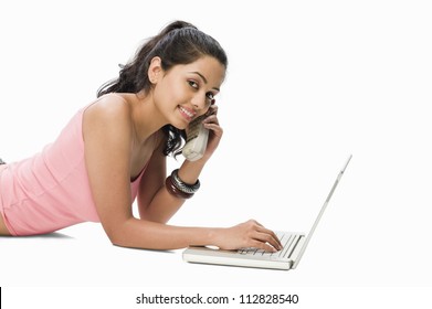 Young Woman Using A Laptop And Talking On A Cordless Phone