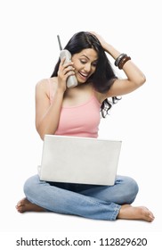 Young Woman Using A Laptop And Talking On A Cordless Phone