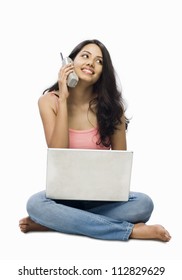 Young Woman Using A Laptop And Talking On A Cordless Phone