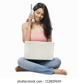 Young Woman Using A Laptop And Talking On A Cordless Phone