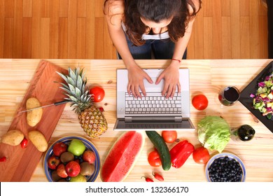 A Young Woman Using A Laptop While Cooking.