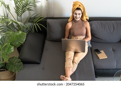 Young woman using laptop while having skin care day at home  - Powered by Shutterstock