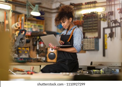 Young woman using a laptop in a workshop - Powered by Shutterstock