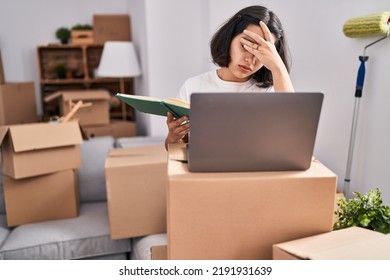 Young Woman Using Laptop With Worried Expression At New Home