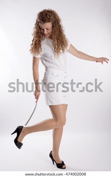 Young woman using a long shoe horn to reach her
high heel shoes