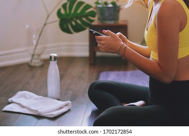 Young woman using mobile phone while practicing yoga at home - Powered by Shutterstock