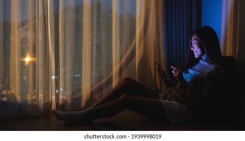 A Young Woman Using Mobile Phone With Bright Light Screen In The Late Night At Home