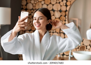 Young woman using mobile phone in bathroom - Powered by Shutterstock