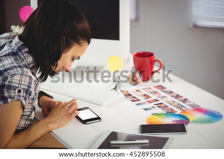 Young woman using mobile phone on table in creative ffice
