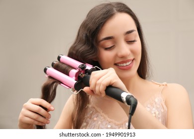 Young Woman Using Modern Curling Iron Indoors