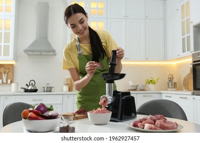 Young woman using modern meat grinder in kitchen