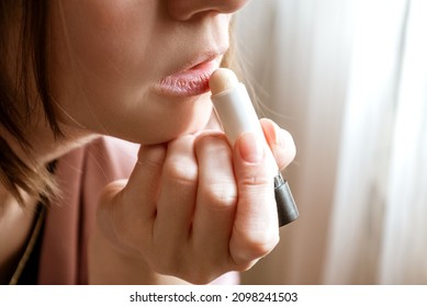 Young woman using moisturizing lipbalm, close up