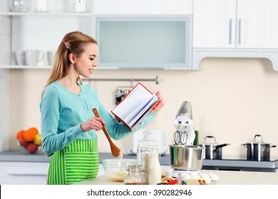 Young Woman Using A Notebook To Follow A Recipe