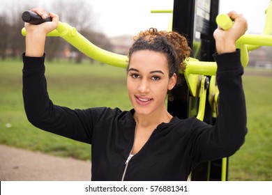 Young Woman Using Outdoor Gym Equipment In The Park