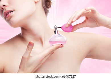 Young woman using perfume on abstract background