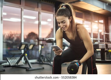 Young Woman Using Phone In Gym.