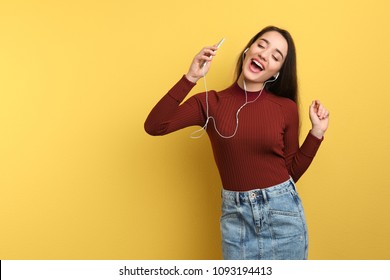 Young Woman Using Phone For Listening To Music On Color Background