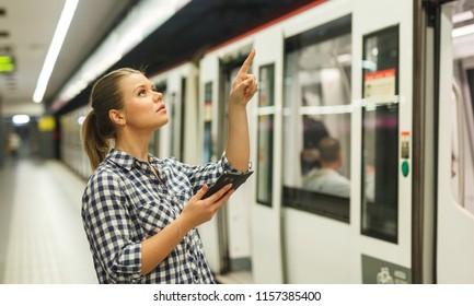 Young woman using phone at subway station, looking for itinerary or destination 