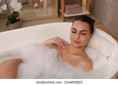 Young woman using pillow while enjoying bubble bath indoors - Powered by Shutterstock