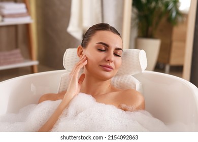 Young woman using pillow while enjoying bubble bath indoors - Powered by Shutterstock