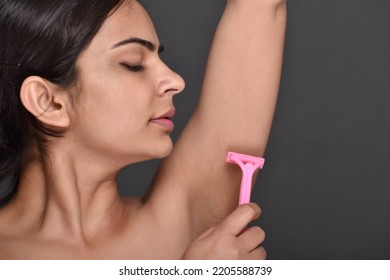 A Young Woman Using Razor To Remove Underarm Hair