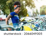 Young woman using rental bike in the city with smart phone