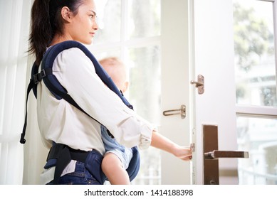 Young Woman Using Sling When Leaving House With Her Little Son