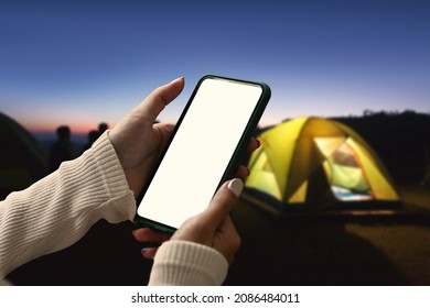 Young Woman Using Smart Phone Near Camping Tent In The Evening.