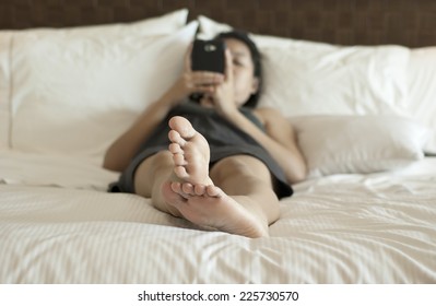 Young Woman Using Smart Phone On The Bed