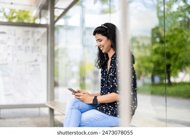 Young woman using smart phone at the bus stop in the city
 - Powered by Shutterstock