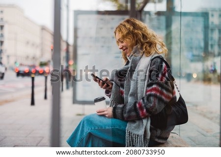 Young woman using smart phone at bus station
