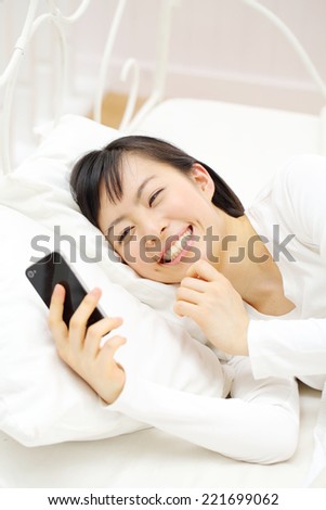 young woman using smart phone on the bed